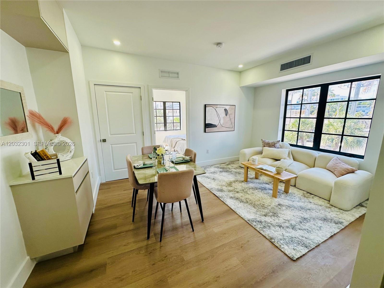 A living and dining area features light wood floors, a white sofa, and a dining table — 1619 Jefferson Ave # 201, Miami Beach FL 33139, MIAMI BEACH, FL