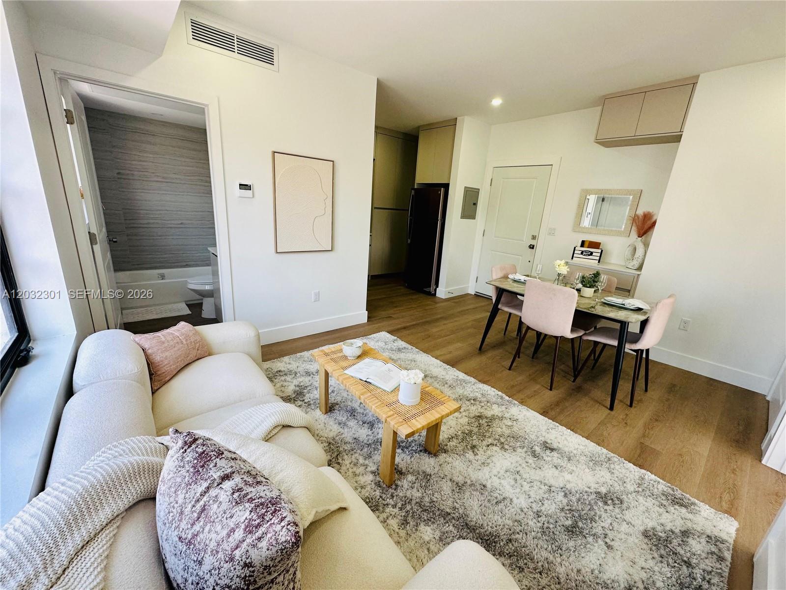 A living room and dining area feature light wood flooring, a white sofa, and rug — 1619 Jefferson Ave # 201, Miami Beach FL 33139, MIAMI BEACH, FL