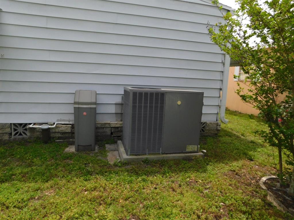 An exterior view of a house showing gray siding, an HVAC unit, and a water softener — 1001 STARKEY ROAD UNIT 99, LARGO, FL