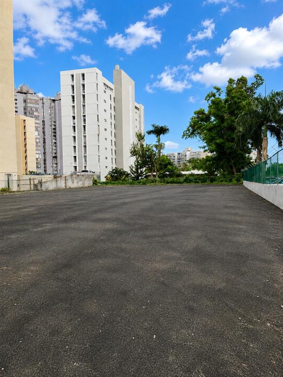 A paved, empty lot sits in front of tall apartment buildings under a blue sky — carr. 2 KM 6.4 VILLA CAPARRA, GUAYNABO, PR