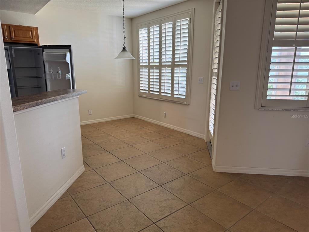A dining area features tan tile flooring, plantation shutters, and a pendant light fixture — 3939 SERENADE LANE UNIT 513, LAKELAND, FL