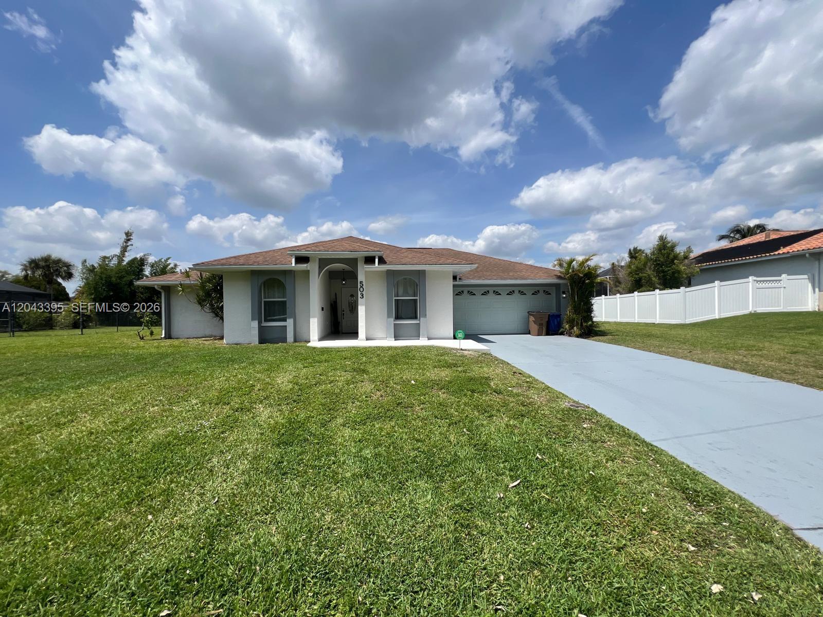 A single-story house with a white exterior, brown roof, and a gray driveway — 503 Jackson, Lehigh Acres FL 33972, LEHIGH ACRES, FL