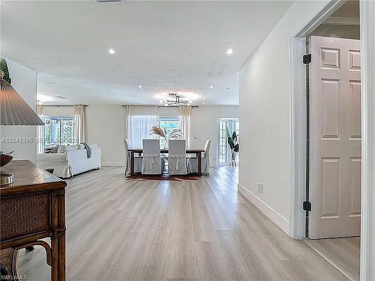 A bright, open-concept living and dining area features light wood flooring and white walls — 503 Jackson, Lehigh Acres FL 33972, LEHIGH ACRES, FL