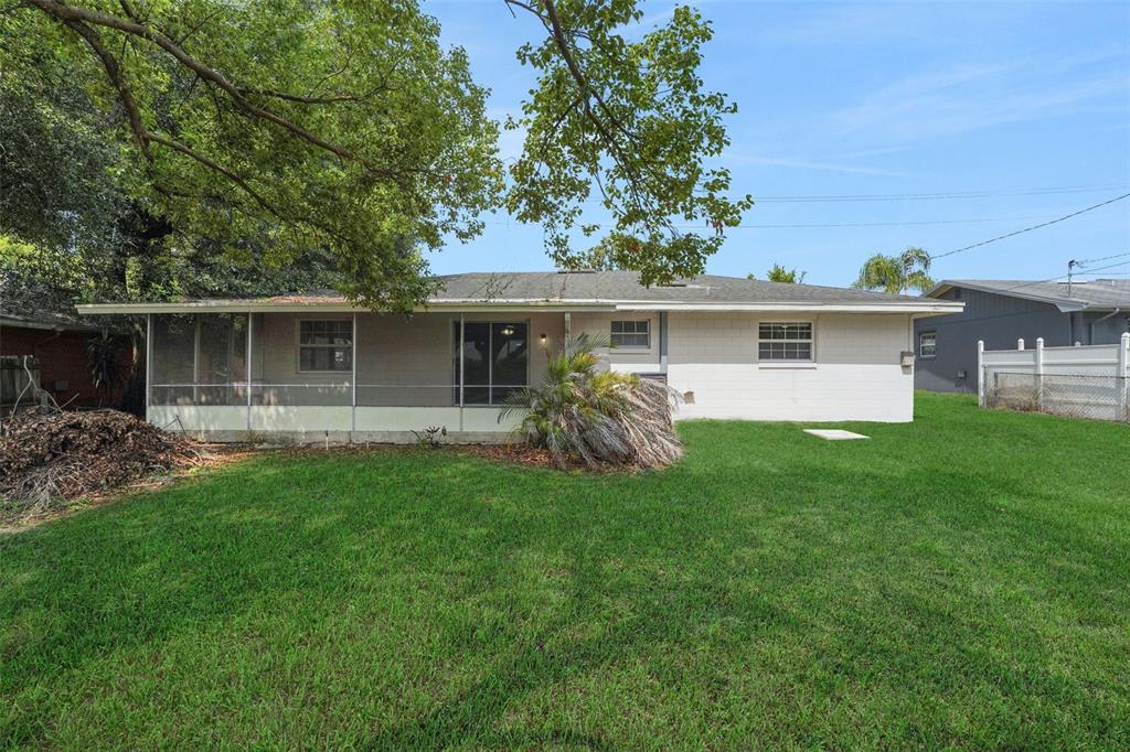 A single-story house with a screened-in porch and a white brick exterior faces a lawn — 404 LAKE NED ROAD, WINTER HAVEN, FL