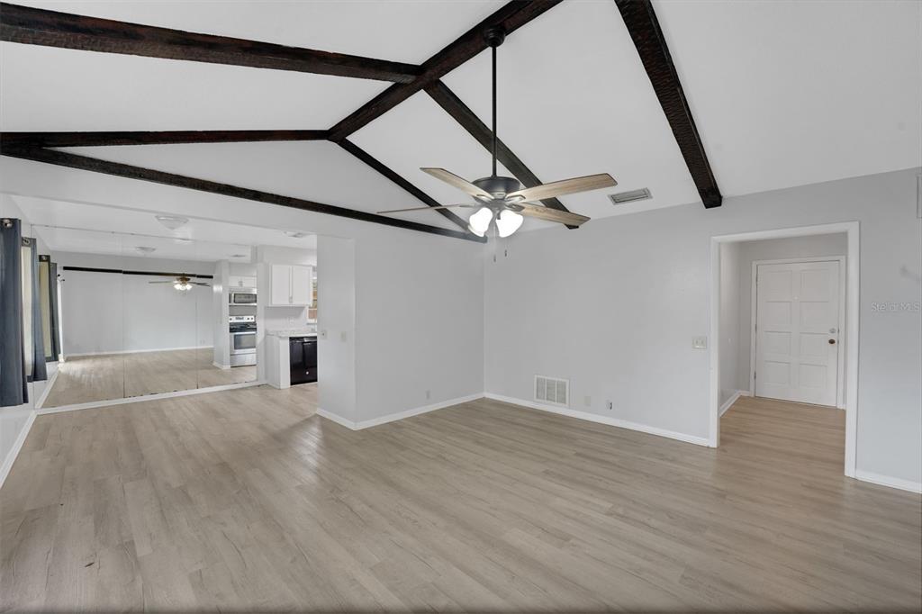 A living room with vaulted ceilings, dark wood beams, light wood flooring, and a ceiling fan — 404 LAKE NED ROAD, WINTER HAVEN, FL