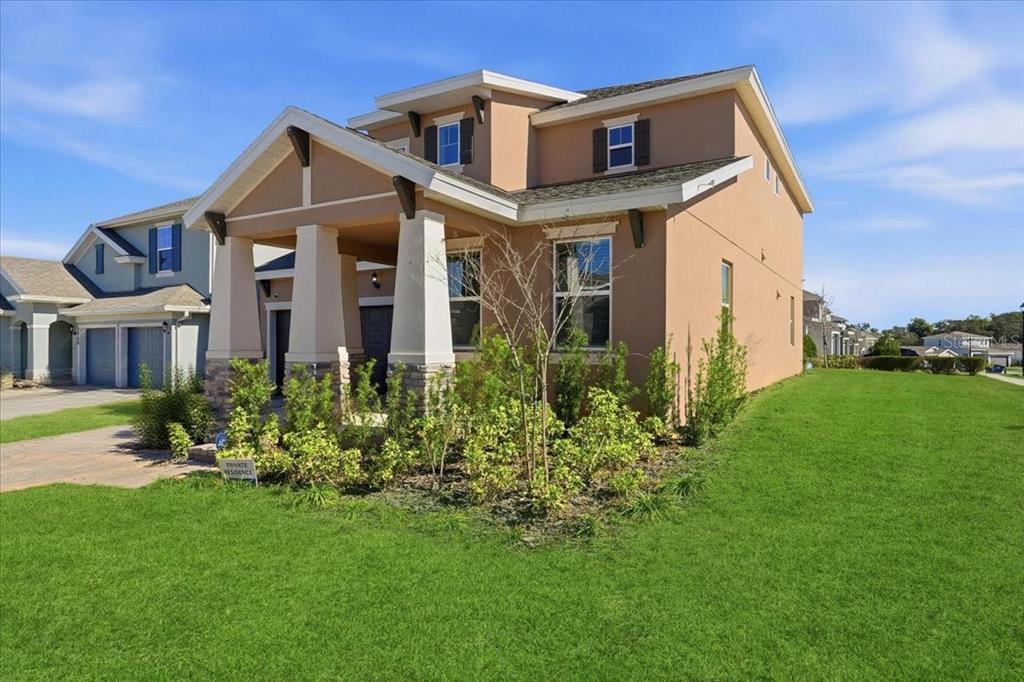 A two-story tan stucco house with a stone-accented front porch and a green lawn — 2072 KEYSTONE PASS BOULEVARD, MINNEOLA, FL