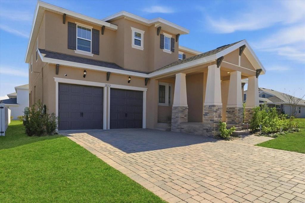 A two-story house with a two-car garage, stone-accented porch, and a paved driveway — 2072 KEYSTONE PASS BOULEVARD, MINNEOLA, FL