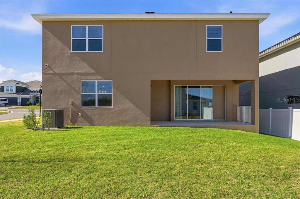 The rear exterior of a two-story house features a covered patio and a grassy yard — 2072 KEYSTONE PASS BOULEVARD, MINNEOLA, FL