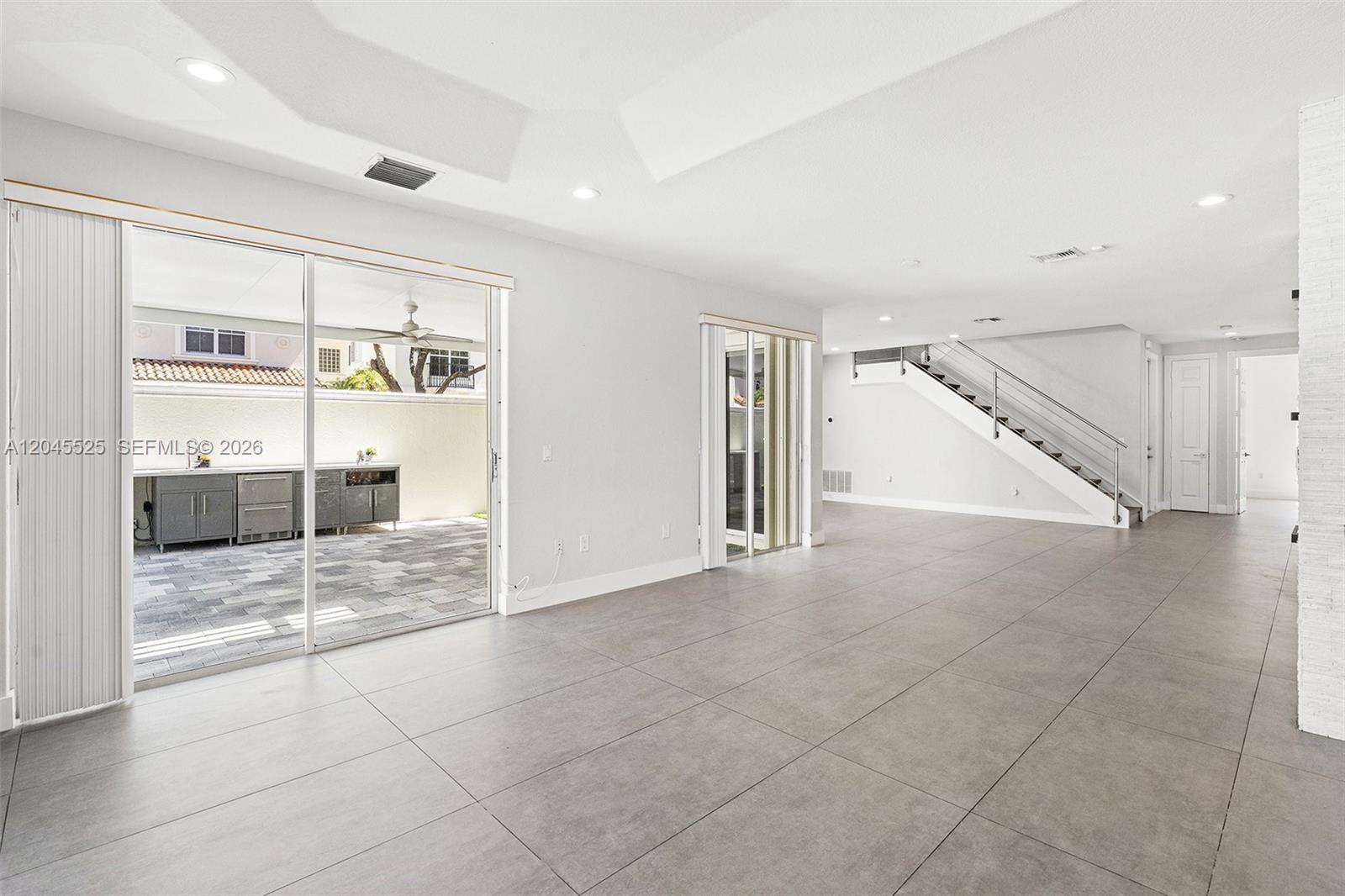 A bright, open-concept living area features large gray floor tiles, recessed lighting, and sliding glass doors — 1549 Shoreline Way, Hollywood FL 33019, HOLLYWOOD, FL
