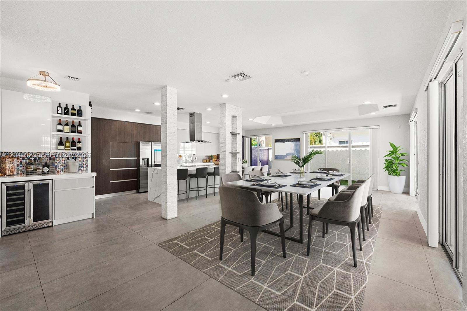 A modern open-concept dining area features a marble table, gray chairs, and a kitchen island — 1549 Shoreline Way, Hollywood FL 33019, HOLLYWOOD, FL