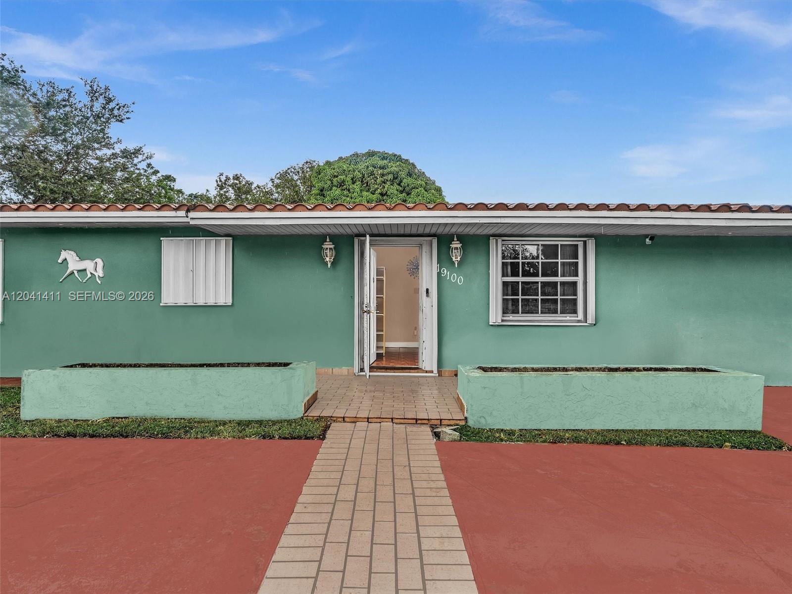 A green single-story house exterior features a tiled walkway, two planters, and a horse silhouette — 19100 NW 51st Ave, Unincorporated Dade County FL 33055, UNINCORPORATED DADE COUNTY, FL