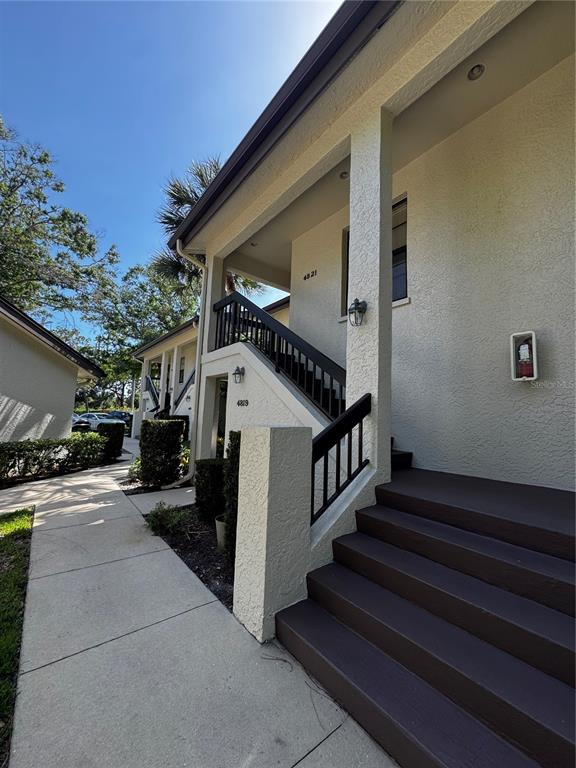 An exterior view of a building with a concrete walkway and dark painted stairs — 4821 WINSLOW BEACON UNIT 42, SARASOTA, FL