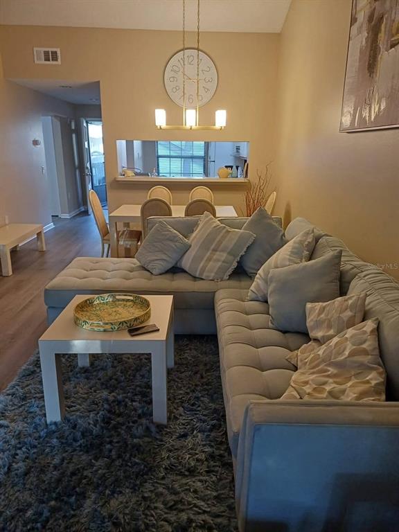 A living room features a tufted sectional sofa, a coffee table, and a dining area — 4821 WINSLOW BEACON UNIT 42, SARASOTA, FL