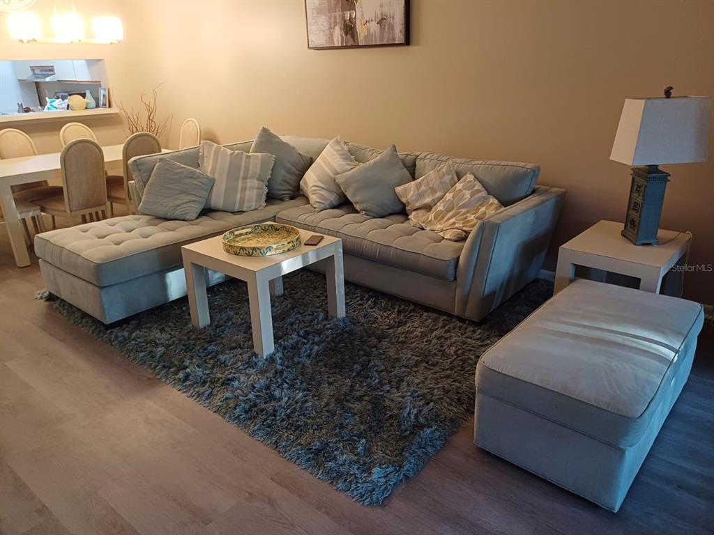 A living room features a large gray sectional sofa, a shag rug, and a side table — 4821 WINSLOW BEACON UNIT 42, SARASOTA, FL