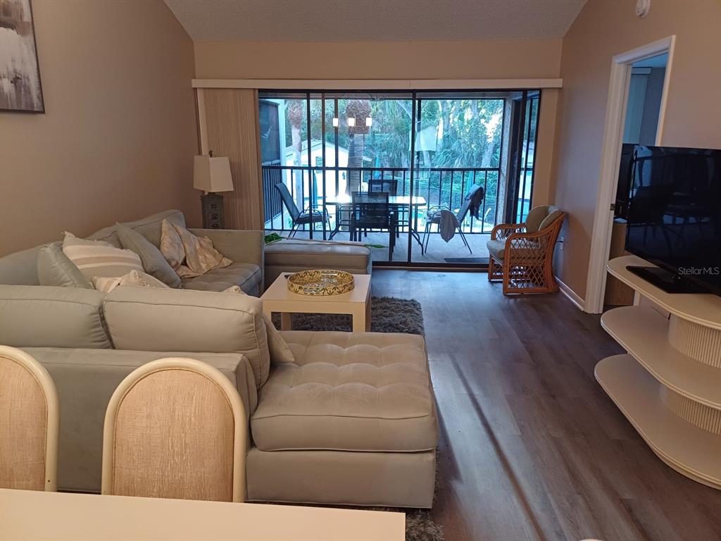 A living room features a sectional sofa, a coffee table, and a sliding glass door — 4821 WINSLOW BEACON UNIT 42, SARASOTA, FL