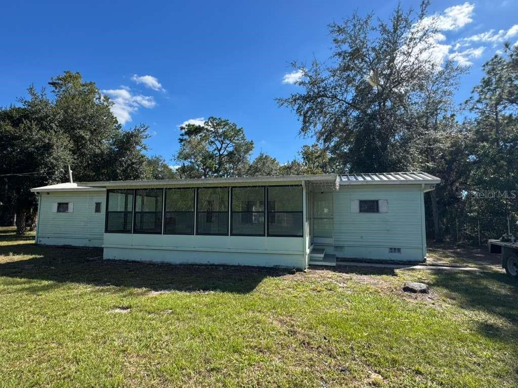 A light green manufactured home features a large screened-in front porch under a metal roof — 6300 W LINDEN DRIVE, HOMOSASSA, FL