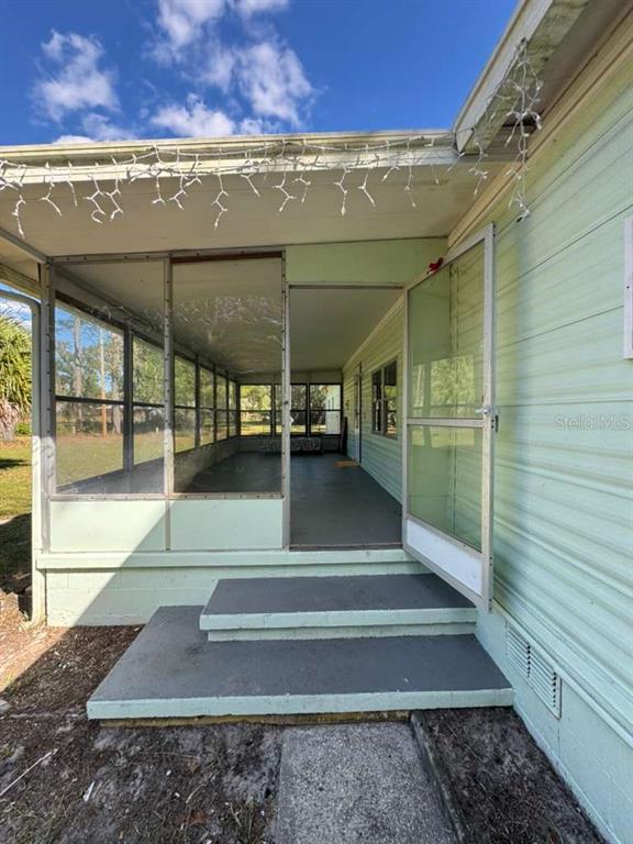 A light green mobile home features a screened-in porch with concrete steps leading to the entrance — 6300 W LINDEN DRIVE, HOMOSASSA, FL