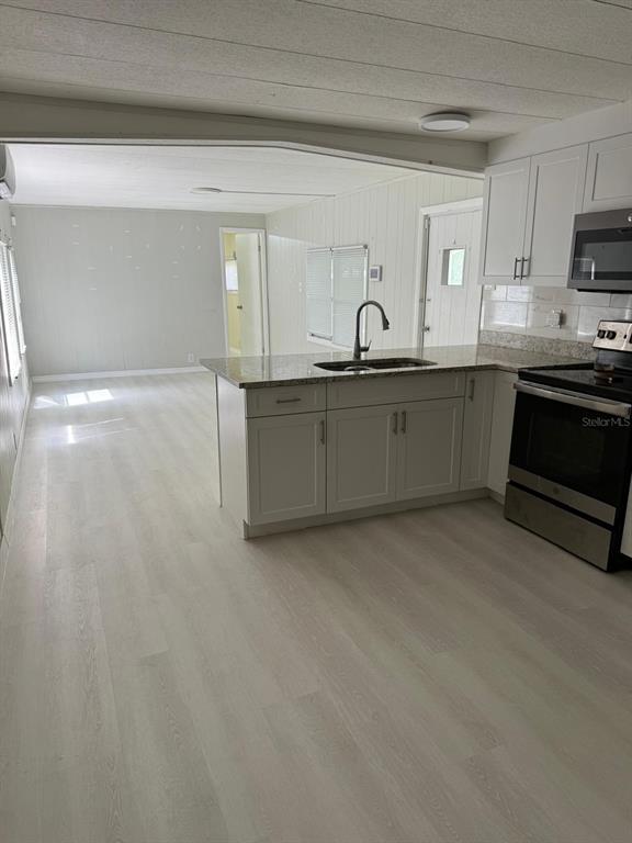 A kitchen with white cabinets, granite countertops, and light wood-look flooring opens to a living area — 6300 W LINDEN DRIVE, HOMOSASSA, FL