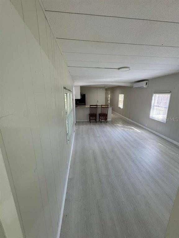 An open-concept living area features light wood-look flooring, white paneled walls, and a kitchen island — 6300 W LINDEN DRIVE, HOMOSASSA, FL