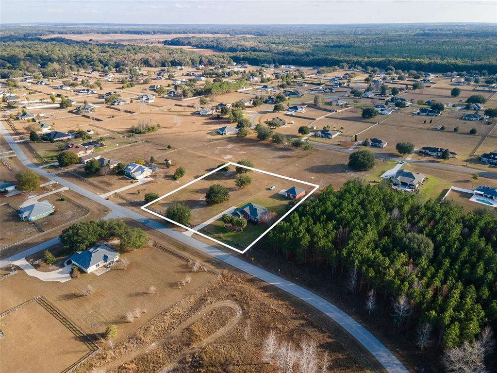 An aerial view shows a residential property with a house and detached garage outlined in white — 10215 SW 98 TH AVENUE, GAINESVILLE, FL