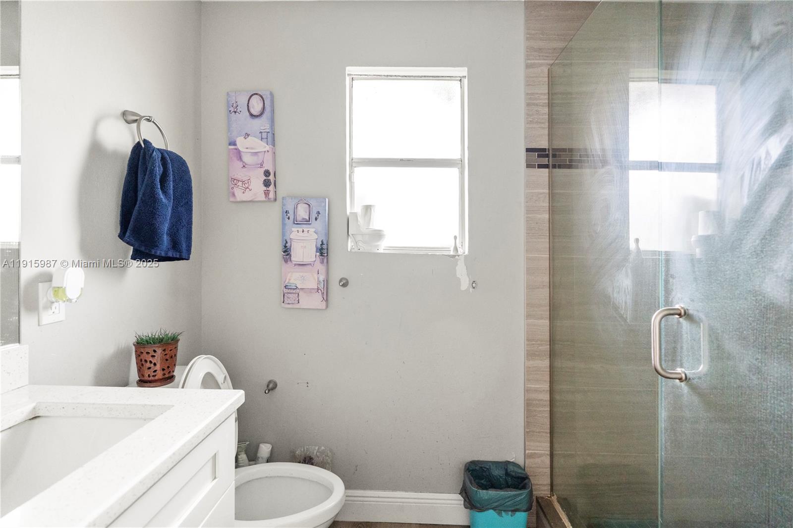 A bathroom features a white vanity, a toilet, a glass-enclosed shower, and wall art — 302 Floyd ave S, Naples FL 33976, NAPLES, FL