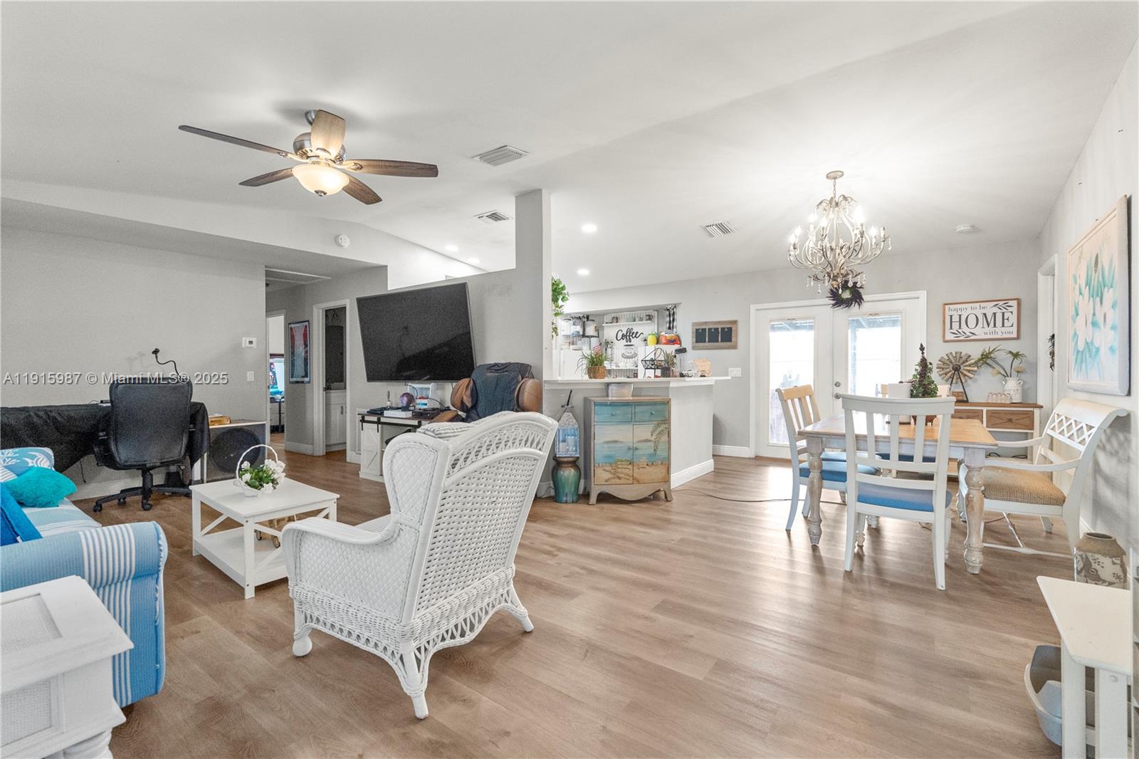 An open-concept living and dining area features light wood flooring, white furniture, and a chandelier — 302 Floyd ave S, Naples FL 33976, NAPLES, FL