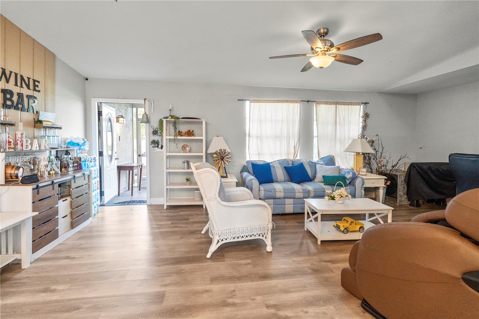 A living room features a striped sofa, a white wicker chair, and a wine bar — 302 Floyd ave S, Naples FL 33976, NAPLES, FL