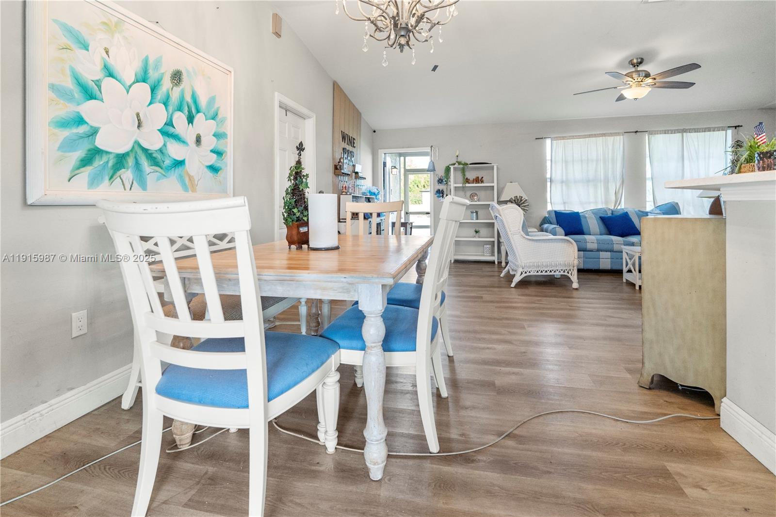 A dining area with a wooden table and blue chairs opens into a living room — 302 Floyd ave S, Naples FL 33976, NAPLES, FL