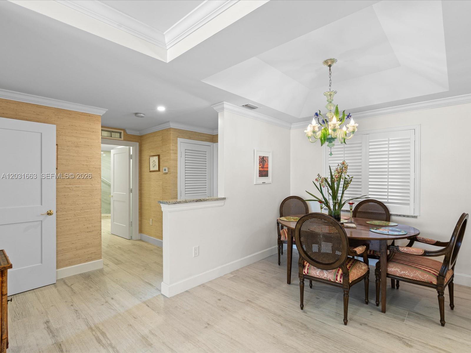 A dining area features a round wooden table, cane-back chairs, and a decorative chandelier — 2160 Ibis Isle Rd # 3, Palm Beach FL 33480, PALM BEACH, FL