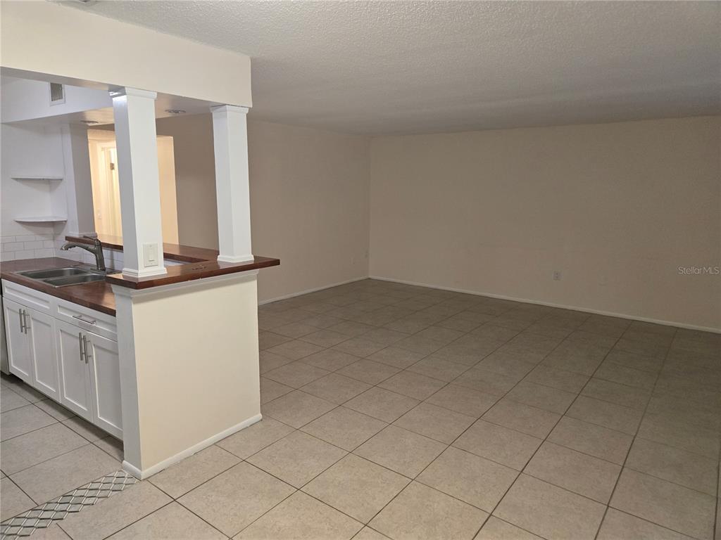 A kitchen with white cabinets and a breakfast bar opens into a tiled living area — 350 79TH AVENUE N UNIT 334, ST PETERSBURG, FL