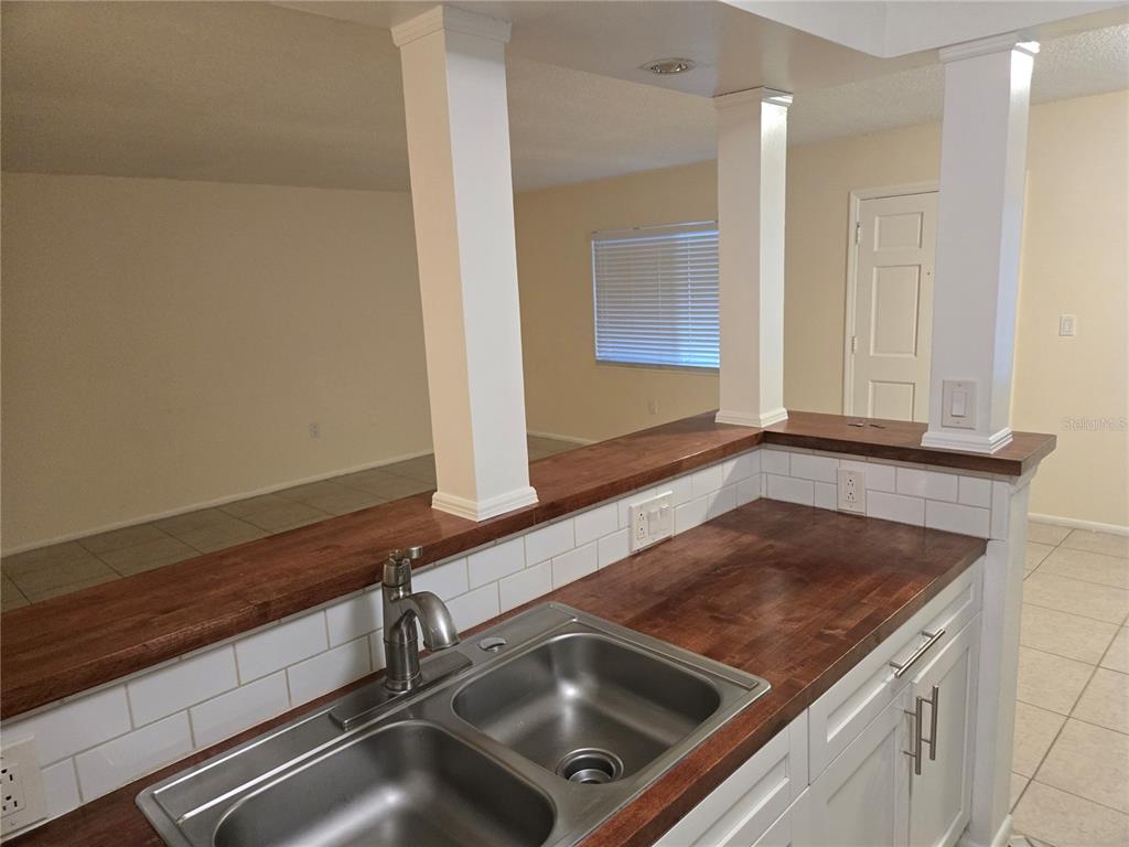 A kitchen sink with a wood countertop and white subway tile backsplash features two columns — 350 79TH AVENUE N UNIT 334, ST PETERSBURG, FL