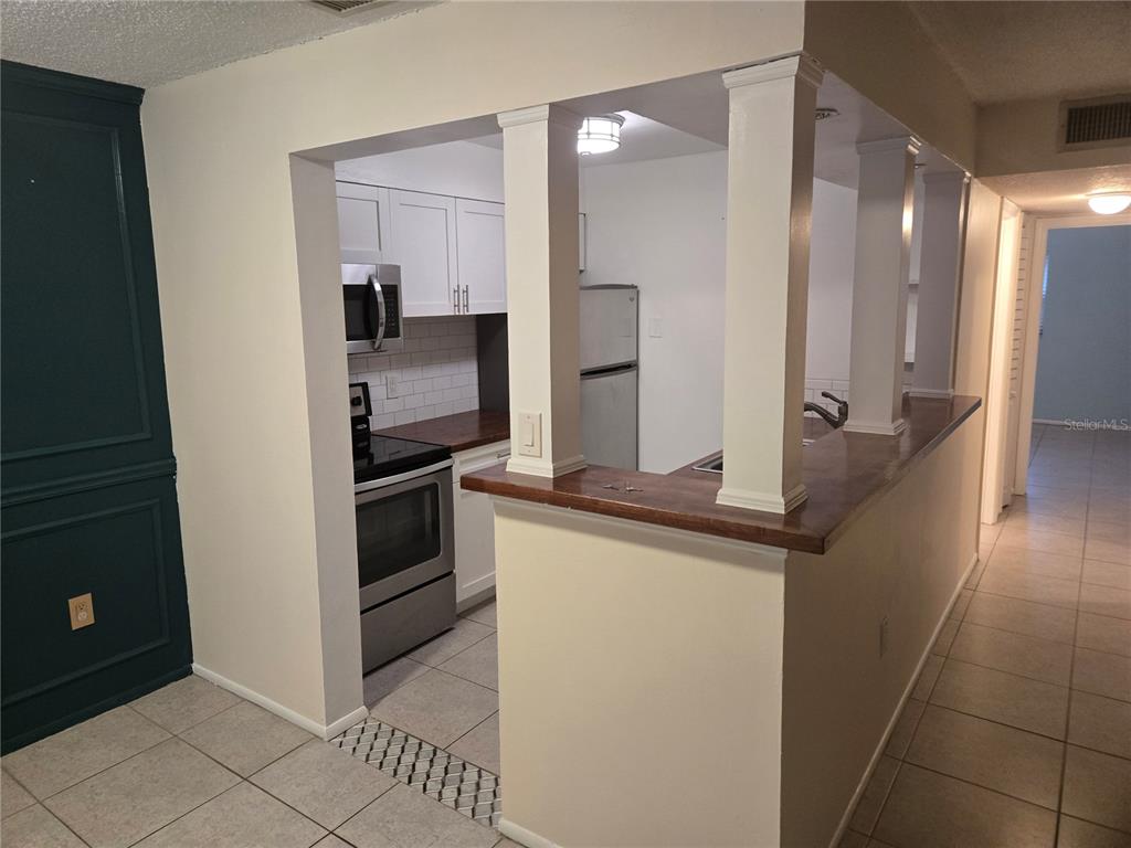 A kitchen with white cabinets, stainless steel appliances, and a breakfast bar with white columns — 350 79TH AVENUE N UNIT 334, ST PETERSBURG, FL