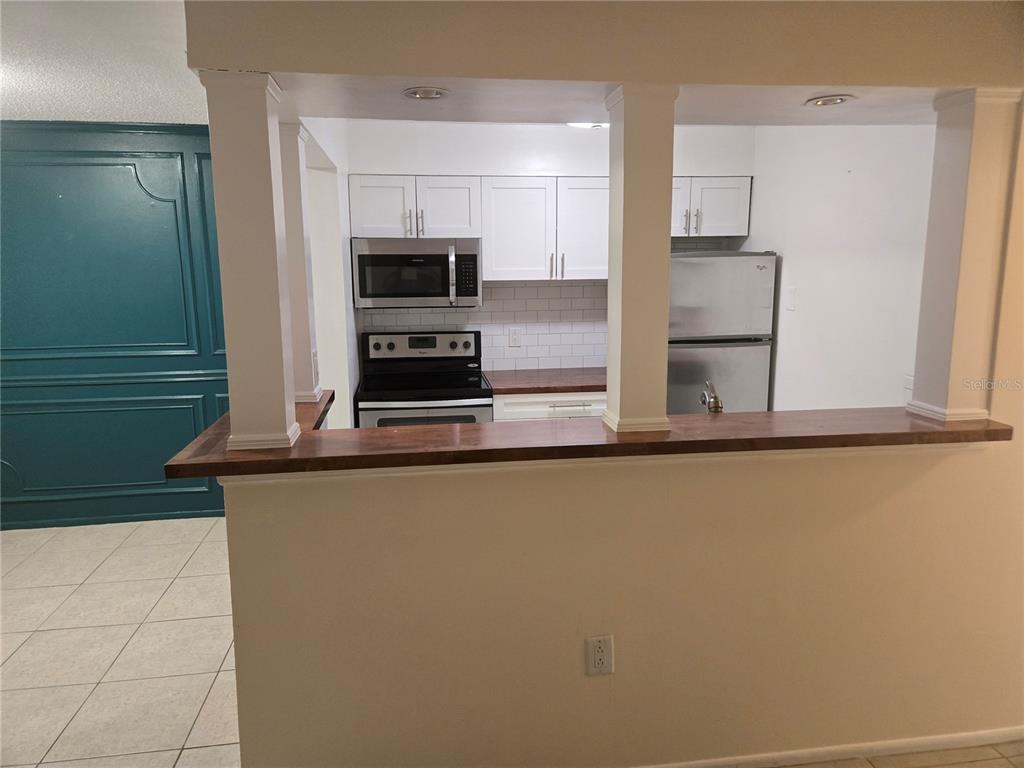 A kitchen with white cabinets, stainless steel appliances, and a wood-topped breakfast bar — 350 79TH AVENUE N UNIT 334, ST PETERSBURG, FL