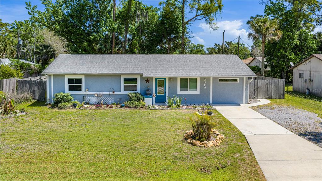 A single-story house with a blue exterior, gray roof, and a concrete driveway — 3309 WOODLAND DRIVE, EDGEWATER, FL