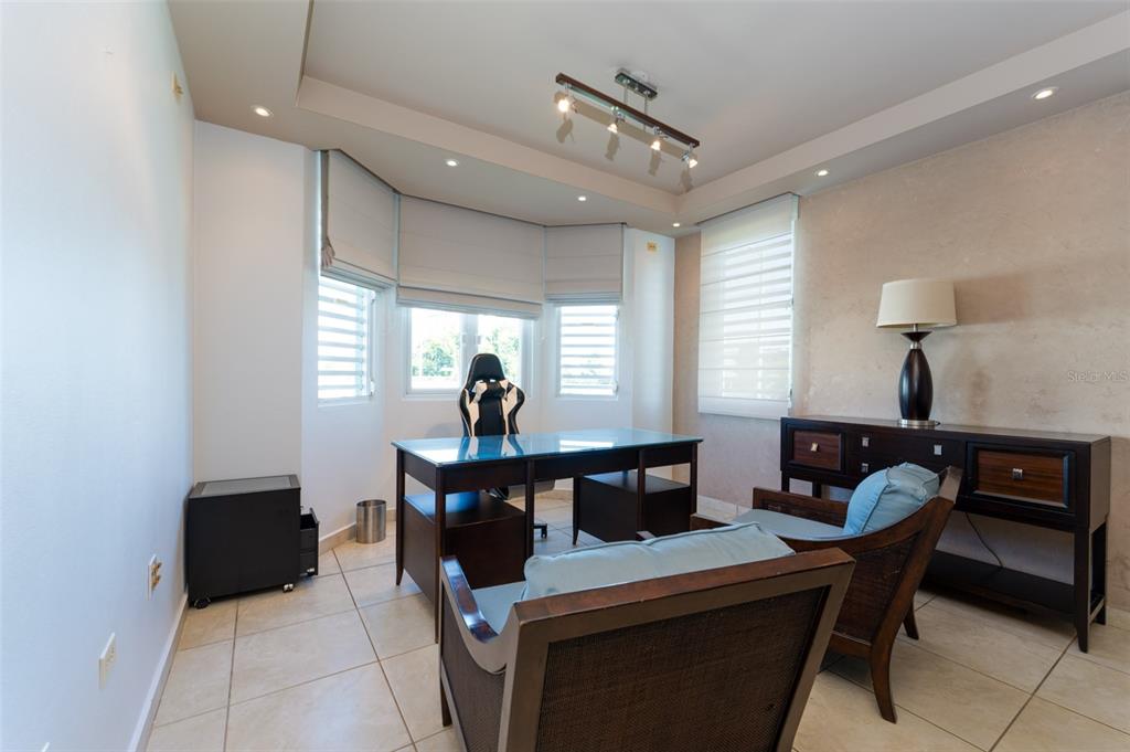 A home office features a glass desk, gaming chair, two armchairs, and a dark wood console — 797 MAR DE CASPIO, DORADO, PR