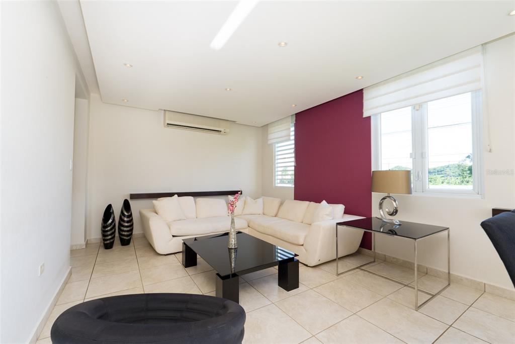 A living room features a white sectional sofa, a black coffee table, and a maroon accent wall — 797 MAR DE CASPIO, DORADO, PR