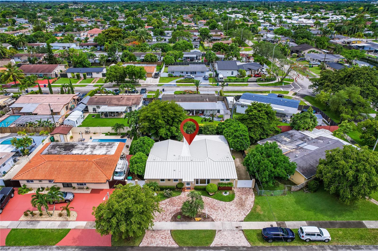 An aerial view shows a single-story house with a white metal roof and brick driveway — 11180 SW 58th Ter, Miami FL 33173, MIAMI, FL