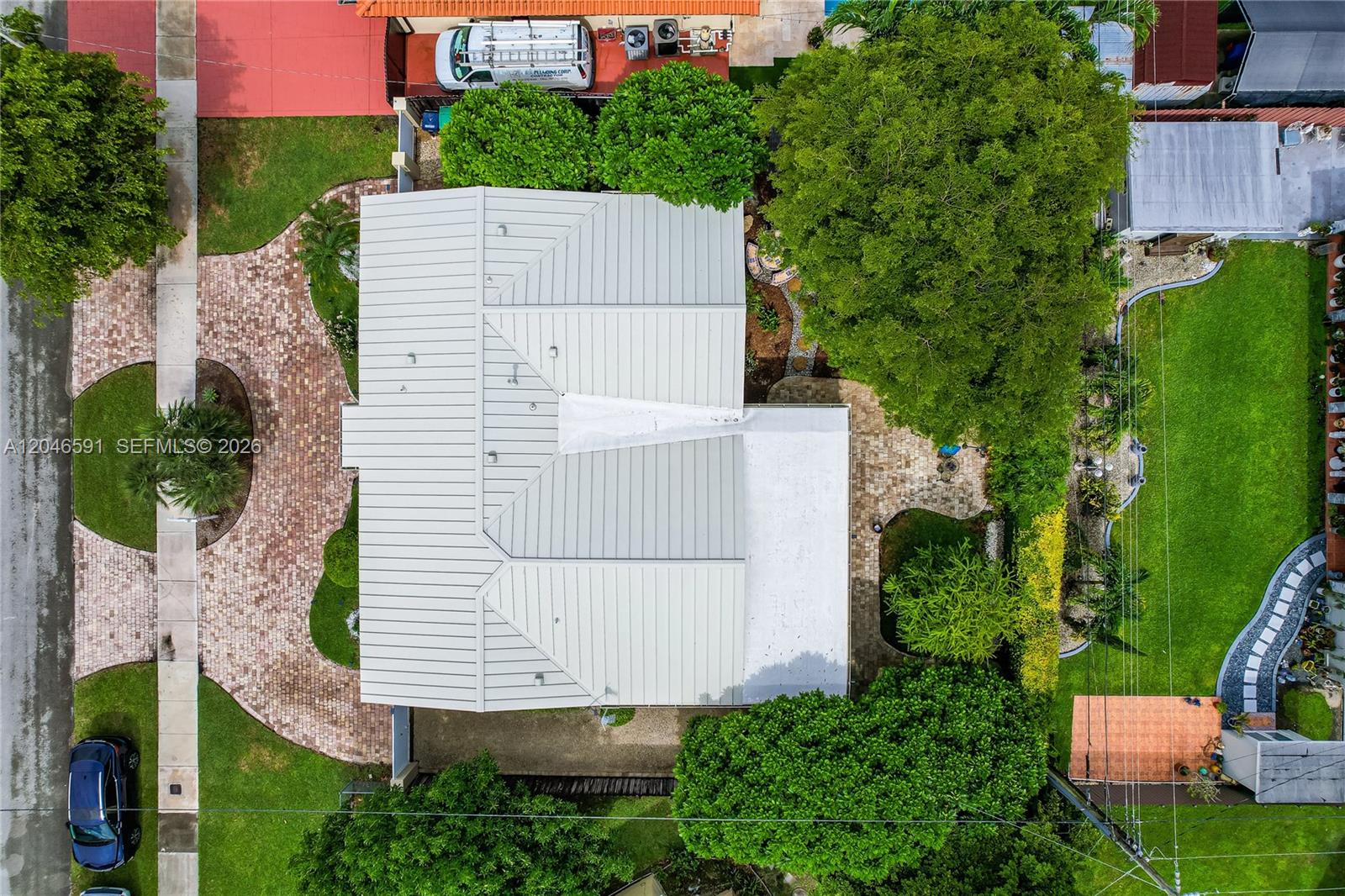 An aerial view shows a house with a metal roof, brick driveway, and landscaped yard — 11180 SW 58th Ter, Miami FL 33173, MIAMI, FL
