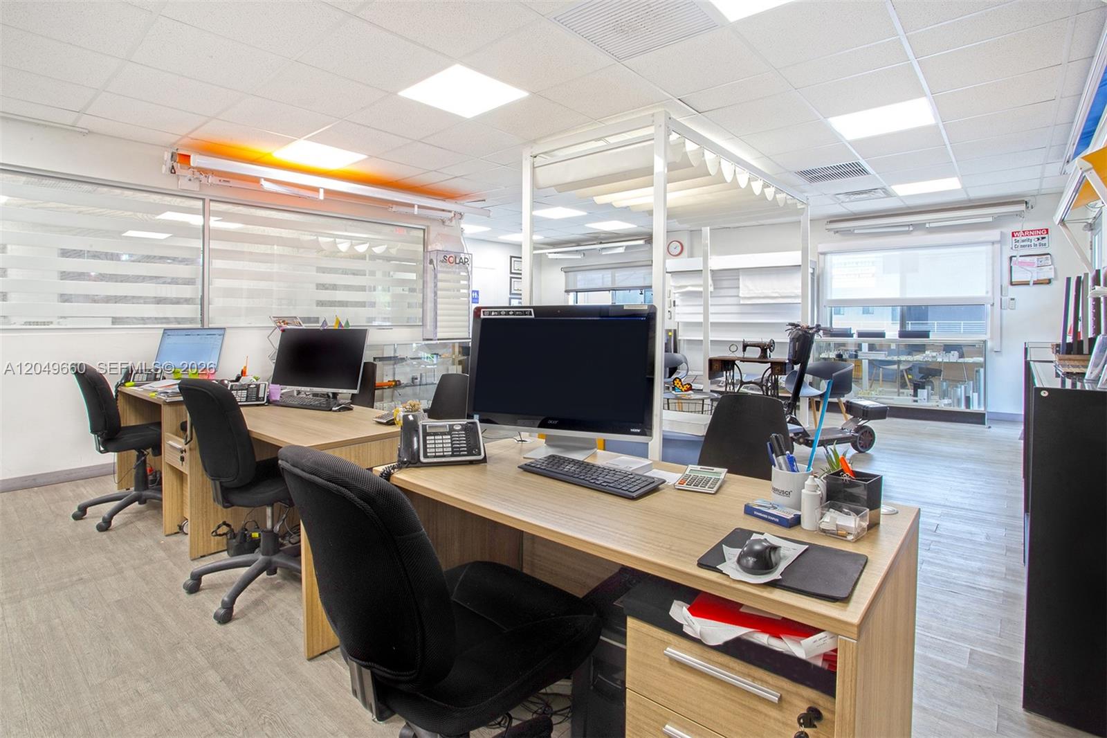 An office space features multiple desks with computers, rolling chairs, and light wood-grain flooring — 2290 W 8th Ave, Hialeah FL 33010, HIALEAH, FL