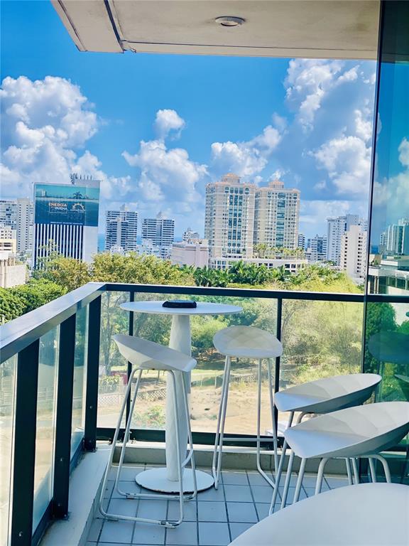 A balcony features a white bistro table and four stools overlooking a city skyline — 1511 PONCE DE LEON AVENIDA UNIT 1052, SAN JUAN, PR