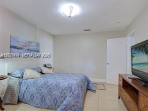 A bedroom features a bed with a blue patterned comforter and a wall-mounted television — 3305 SW 114 CT # 2, Miami FL 33165, MIAMI, FL