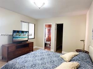 A bedroom features a bed with a patterned blue quilt, a wooden dresser, and television — 3305 SW 114 CT # 2, Miami FL 33165, MIAMI, FL