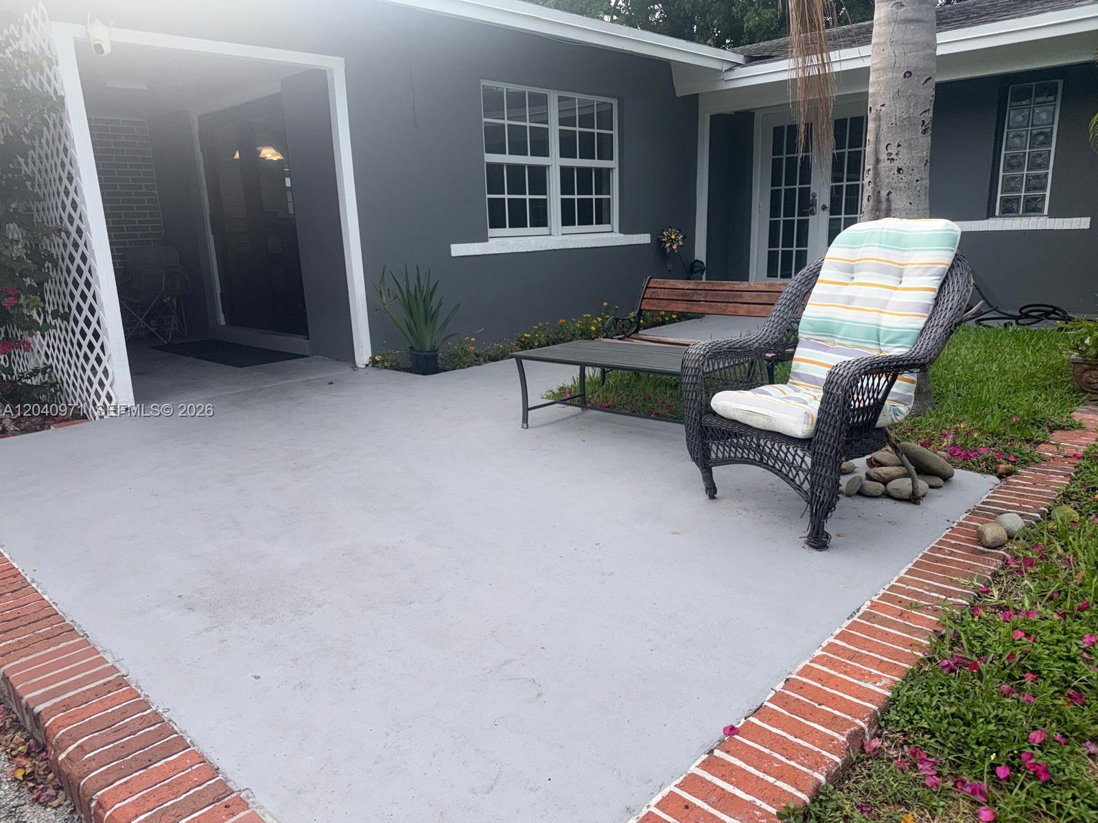 A gray concrete patio features a wicker chair, a bench, and a small table — 12551 SW 35th St, Miami FL 33175, MIAMI, FL