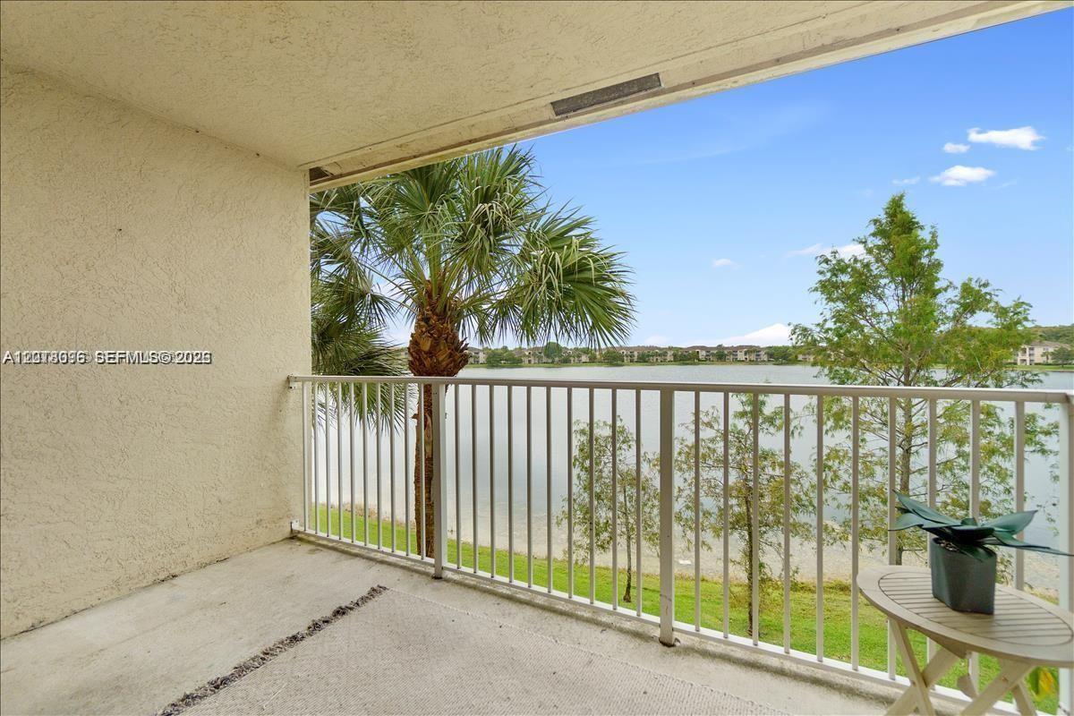 A balcony with a white metal railing overlooks a lake and palm trees — 5065 Wiles Rd # 308, Coconut Creek FL 33073, COCONUT CREEK, FL