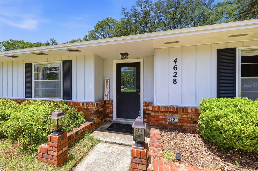 The exterior of a single-story house features a brick base, white siding, and a front door — 4628 NW 40TH STREET, GAINESVILLE, FL