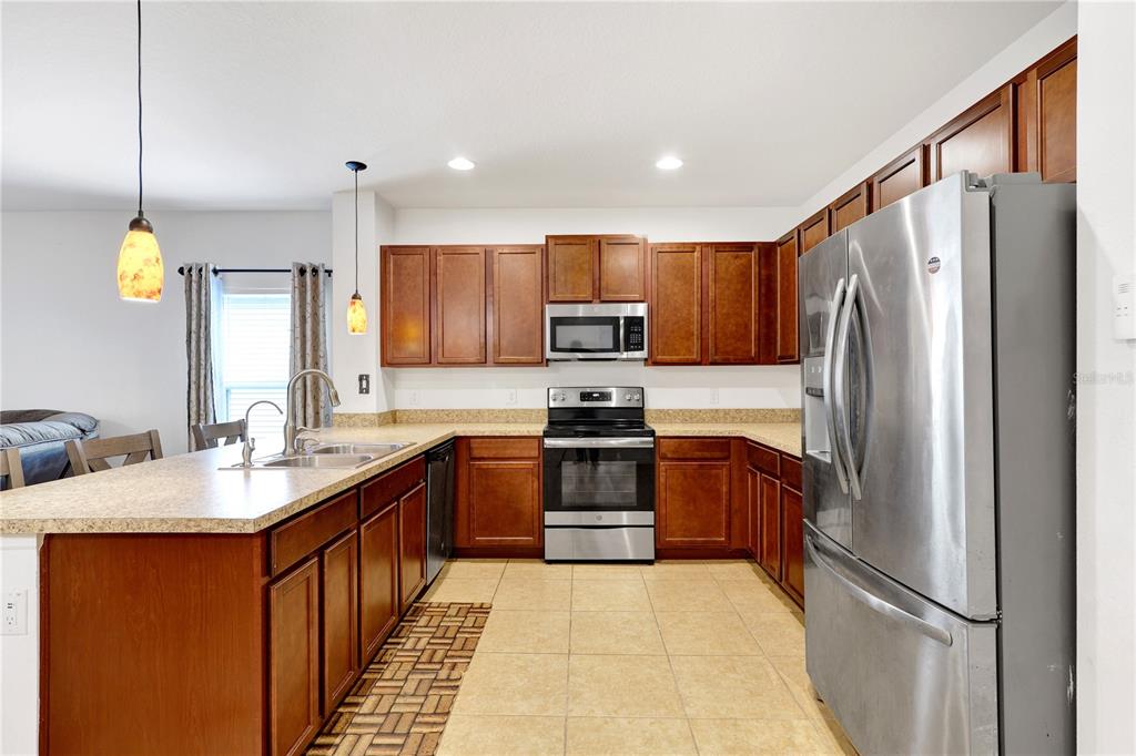 A kitchen with wood cabinets, stainless steel appliances, and a large island with a sink — 4817 MARCOS CIRCLE, KISSIMMEE, FL