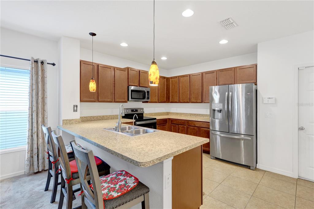 A kitchen features wood cabinets, stainless steel appliances, a breakfast bar, and tile flooring — 4817 MARCOS CIRCLE, KISSIMMEE, FL