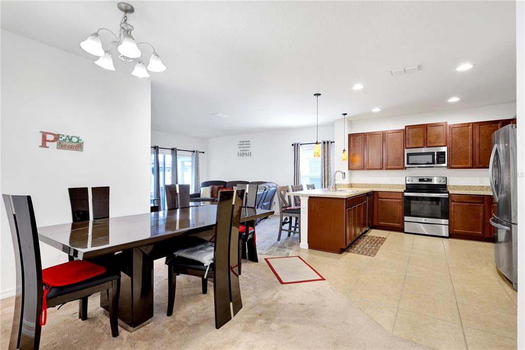 An open-concept kitchen and dining area features dark wood cabinets and a large dining table — 4817 MARCOS CIRCLE, KISSIMMEE, FL
