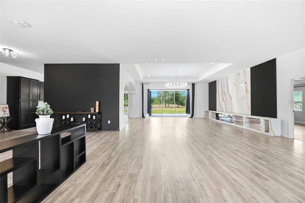 A spacious living room features light wood flooring, a black accent wall, and marble fireplace — 18043 PALMDALE ROAD, WEEKI WACHEE, FL