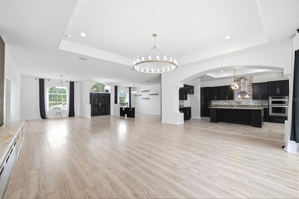 A spacious open-concept living area features light wood-look tile flooring and a modern kitchen — 18043 PALMDALE ROAD, WEEKI WACHEE, FL